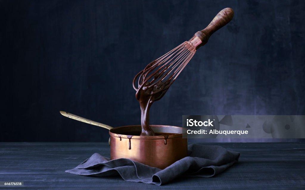 Copper Pot Floating wish dipped into copper pot of chocolate ganache Chocolate Stock Photo