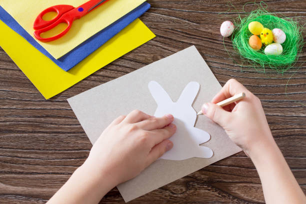istock Child draws items crafts. Create Easter baby gift napkin holder paper easter bunny. Made by hand. Children's Art Project, needlework, crafts for children. 646179178