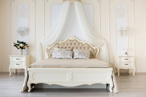 istock Bedroom in soft light colors. Big comfortable double bed in elegant classic interior 646179238
