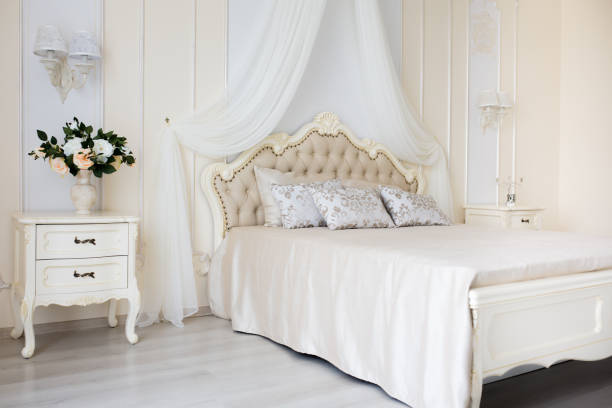 istock Bedroom in soft light colors. Big comfortable double bed in elegant classic interior 646179464