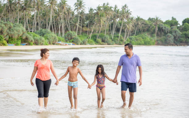 istock Family with two children holding hands on beach 646182336