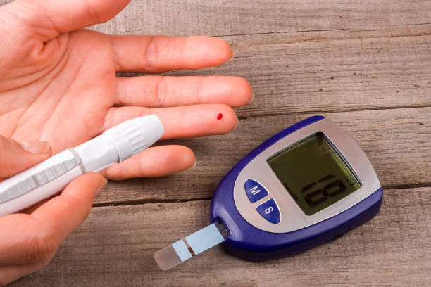 istock blood glucose meter with a hand on an old wooden background 646182432