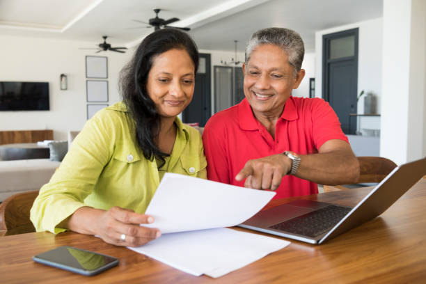 istock Couple using laptop and looking at paperwork 646182558