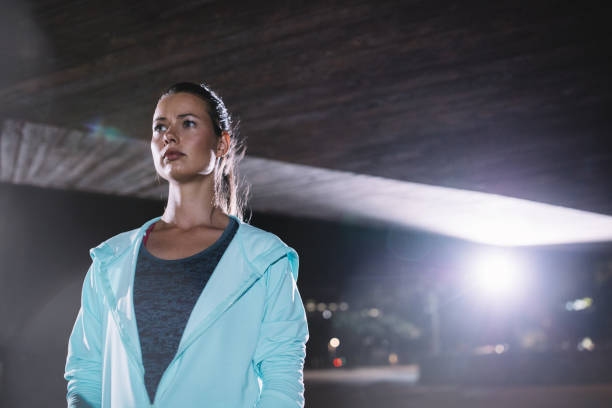 istock Female runner standing under bridge at night 646183972