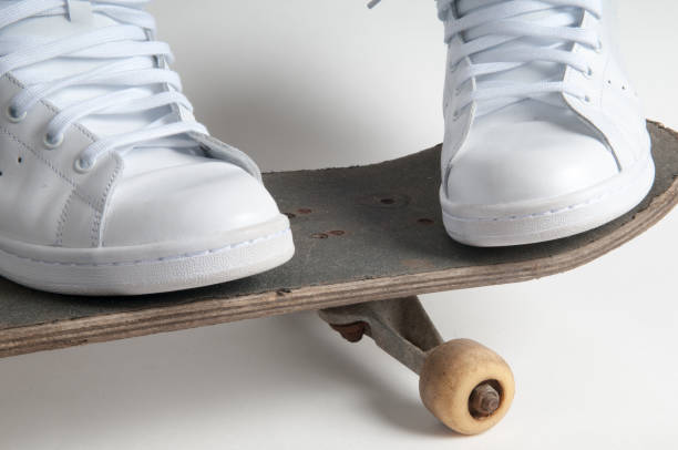 Closeup image of man's legs standing on skate board. Man skateboarding on city street.