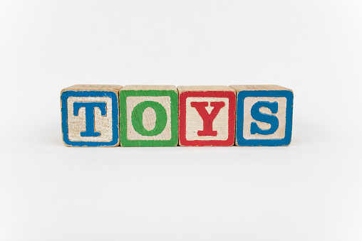 Toys - Isolated Text Word In Wooden Childrens Building Blocks with a White Background. The blocks are intentionally worn, giving a more authentic or played with look.