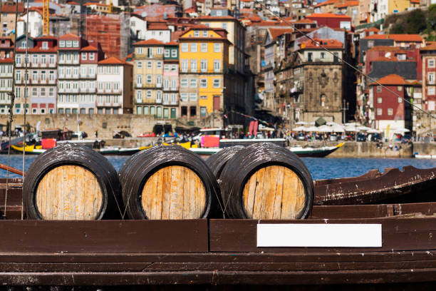 port de barriques de vin dans un bateau dans le fleuve douro avec la ville de porto en arrière-plan - portugal port wine porto the douro photos et images de collection