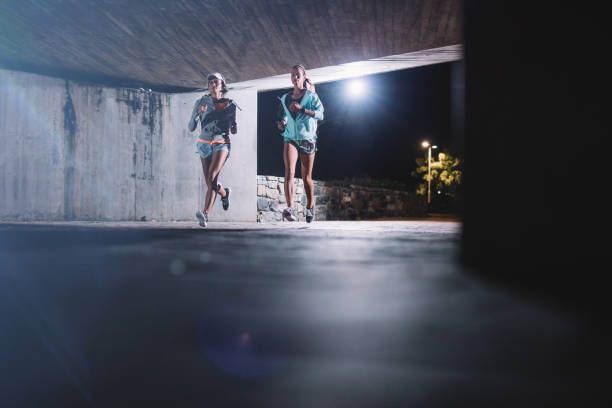 istock Young women jogging under bridge at night 646186958