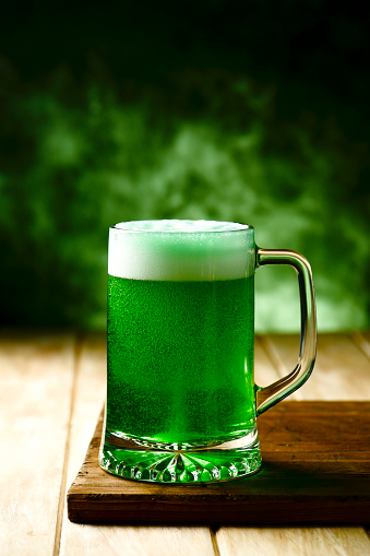 closeup of a glass jar with dyed green beer on a wooden rustic surface