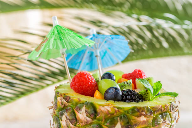 Tropical fruits salad in pineapple on sandy beach