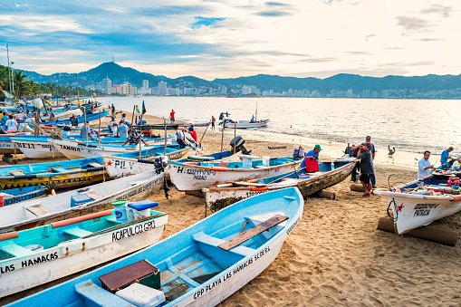 Fishermen stand by their boats and sell freshly caught fish on a beach in Acapulco, Guerrero state, Mexico in the morning.