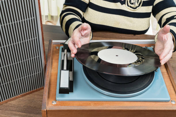 istock Old woman puts a vinyl record 646207426