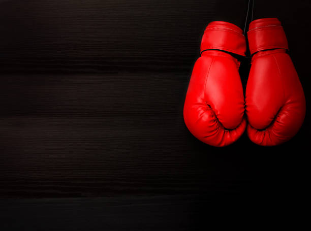 istock Two red boxing gloves in the upper corner of the frame over a black background, empty space 646231576