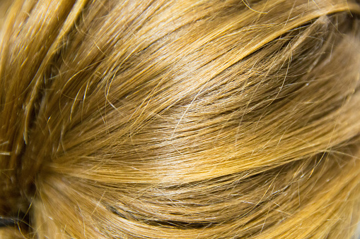 Blonde hair on a woman's head as a background. Back view.