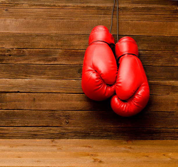 istock Two red boxing gloves hung on a wooden brown background, empty space 646231706