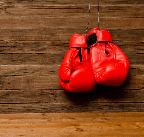 istock Two red boxing gloves hung on a wooden brown background, empty space 646231806