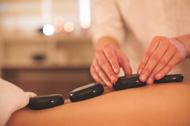istock Close up of massage therapyst hands using lava stones 646234704