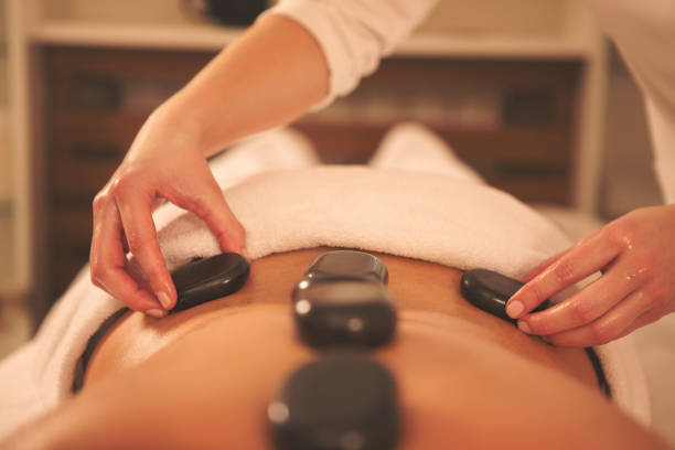 istock Close up of massage therapyst using lava stones 646235230