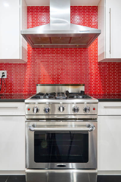 Modern designed kichen Modern designed kitchen with white cabinets, red back splash, stainless steel range oven and hood. red kitchen cabinets stock pictures, royalty-free photos & images