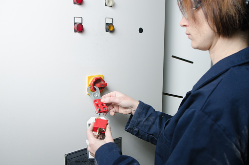 Woman worker locking out electrical box for safety before servicing an equipment