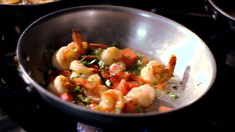 A chef adds seasonings to a skillet.