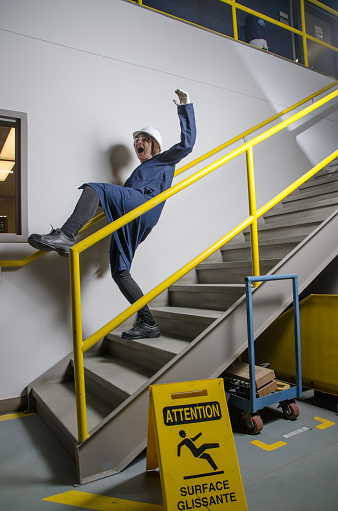 Woman worker falling down the stairs in a factory.
