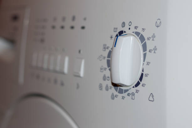 istock front rotate dial knob of white clothes washing machine - selective focus 646334382