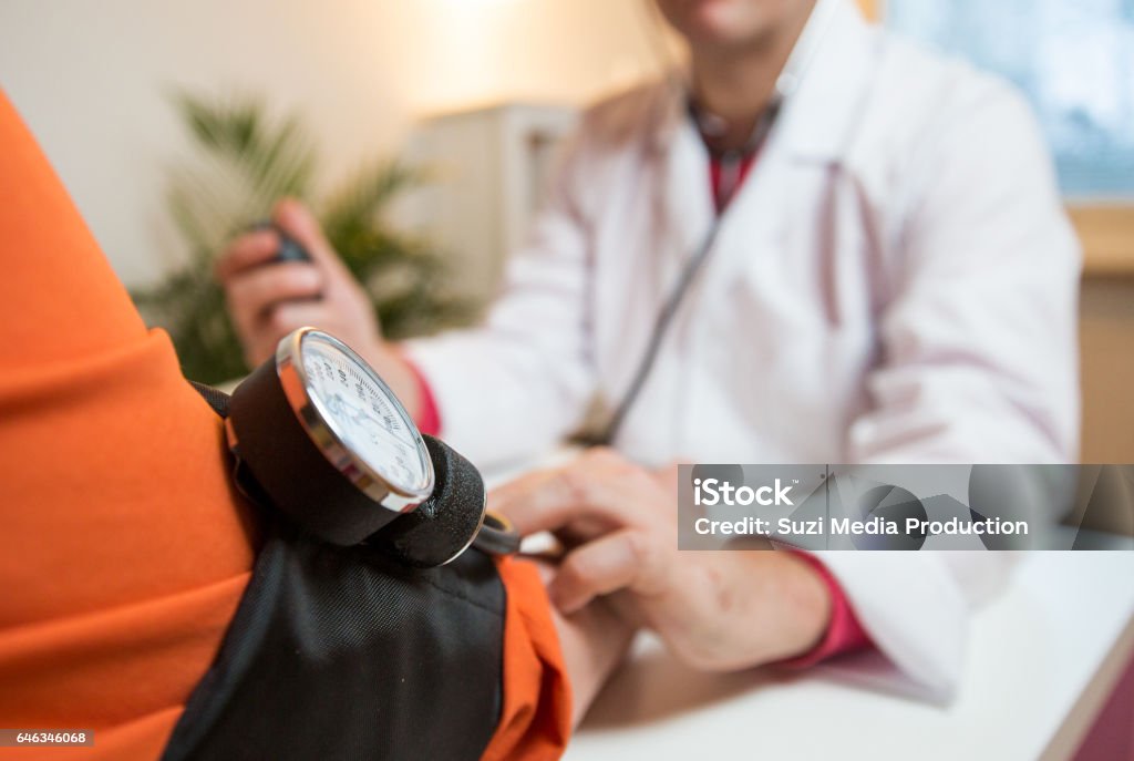 Senior woman having a doctor appointment Male doctor holding hand of patient in hospital. Sick senior woman having a doctor appointment. Trust and support concept. Blood Pressure Gauge Stock Photo