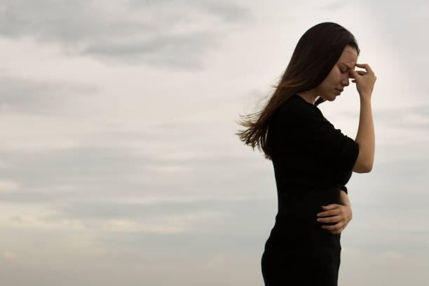 Dreary sky background. Young woman in black shirt. Side profile.