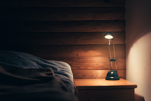 Bedroom lamp on a night table next to a sleeping bed
