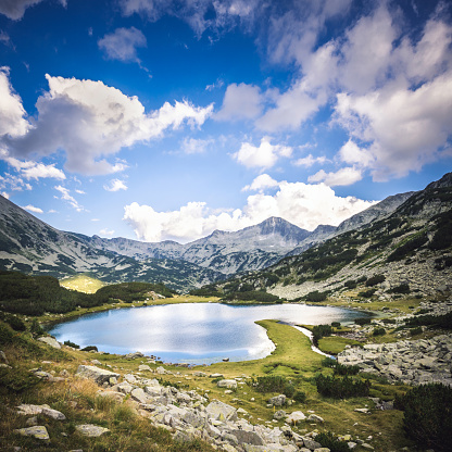 Aerial drone panorama above a lake in Valcea County, Romania. Stormy weather, rain clouds are gathering above the surrounding forests. Several small villages can be seen on the lake's shores.