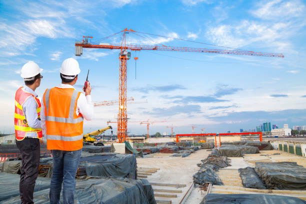 istock Engineer and foreman looking at crane construction with talking on the walkie-talkie for controlling crane loading at construction site 646374798