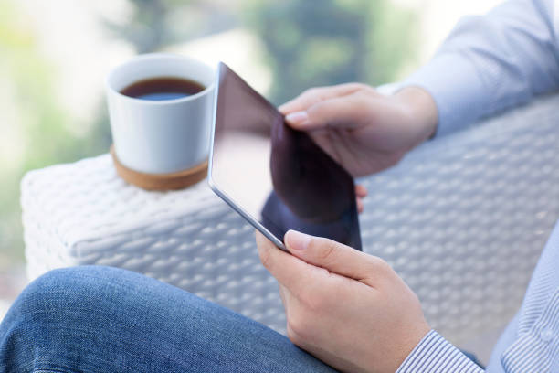 istock man sitting in summer cafe and holding tablet computer 646380628