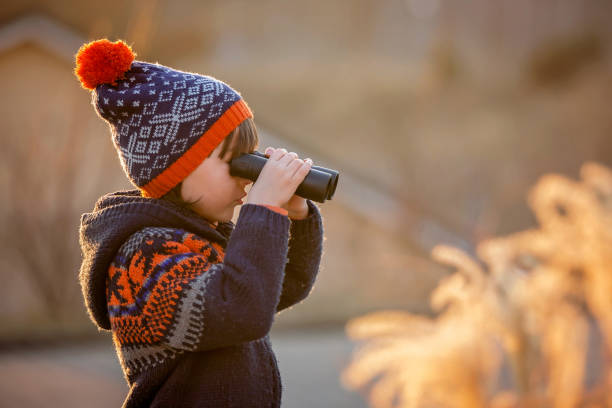 bonito menino pequeno, menino, explorar a natureza com binóculos, olhando o pôr do sol - searching landscape sunset winter - fotografias e filmes do acervo