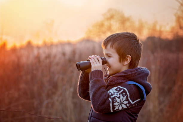 かわいい小さな子供、少年、夕日を見て、双眼鏡で自然を探索 - children only adventure exploration education ストックフォトと画像