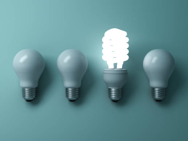 istock Energy saving light bulb , one glowing compact fluorescent lightbulb standing out from unlit incandescent bulbs on green background , individuality and different creative idea concepts 646417760
