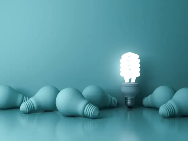 Energy saving light bulb , one glowing fluorescent lightbulb standing out from dead incandescent bulbs on green background , individuality and different creative idea concepts . 3D rendering.