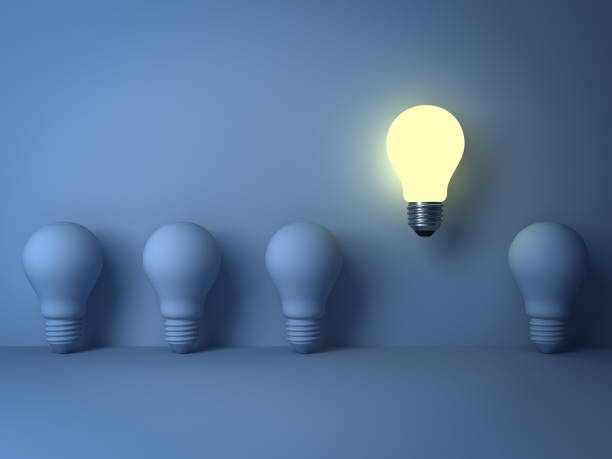 istock One glowing light bulb standing out from the unlit incandescent bulbs on blue background with shadow , The business concept and individuality concept 646418036