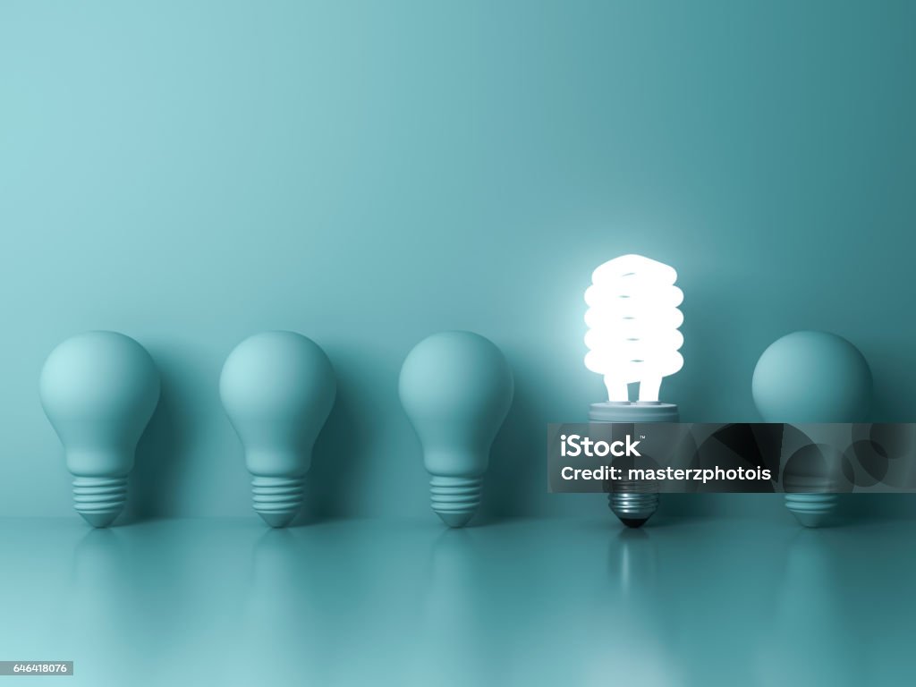 Eco energy saving light bulb , one glowing compact fluorescent lightbulb standing out from unlit incandescent bulbs reflection on green background Eco energy saving light bulb , one glowing compact fluorescent lightbulb standing out from unlit incandescent bulbs reflection on green background , individuality and different concept . 3D rendering. Standing Out From The Crowd Stock Photo