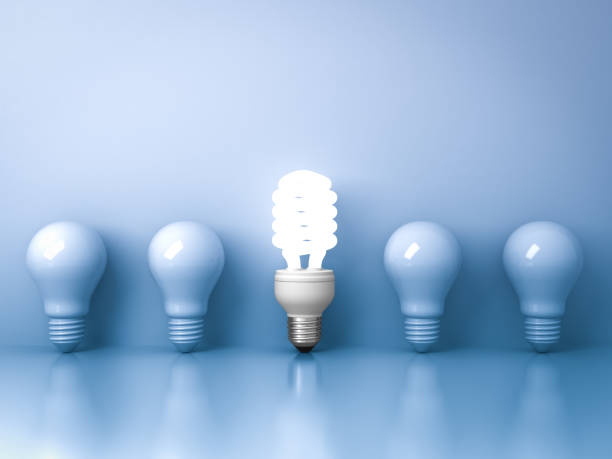 istock Energy saving light bulb , one glowing compact fluorescent lightbulb standing out from unlit incandescent bulbs on blue background individuality and different creative idea concepts 646418138