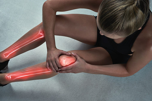 Studio shot of a sporty young woman suffering from a knee injury