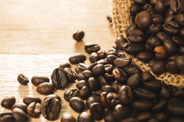 istock Coffee Beans in a burlap bag on wood table 646427614