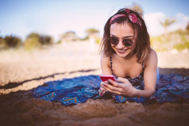 istock Attractive young girl texting and smiling at the beach 646427738