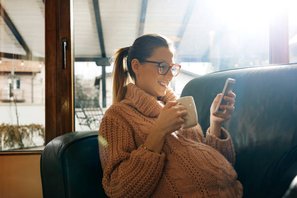 mujer embarazada alegre con su smartphone - women computer home interior brown hair fotografías e imágenes de stock
