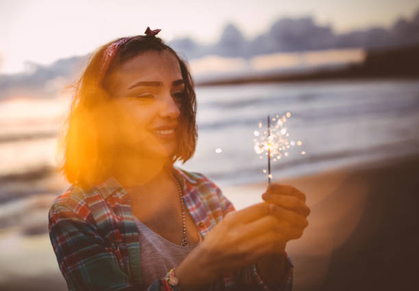 istock Cool young woman with fireworks at seaside at sunset 646428730