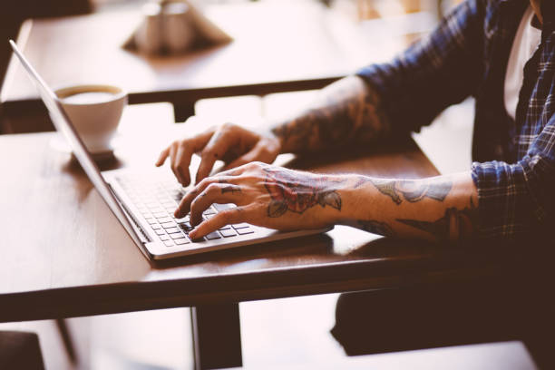 istock Cool man with tatoos typing on laptop in coffee shop 646431176