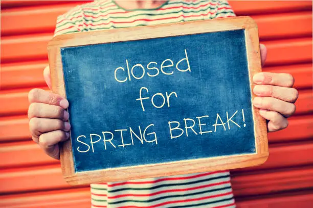 Photo of man and chalkboard with text closed for spring break