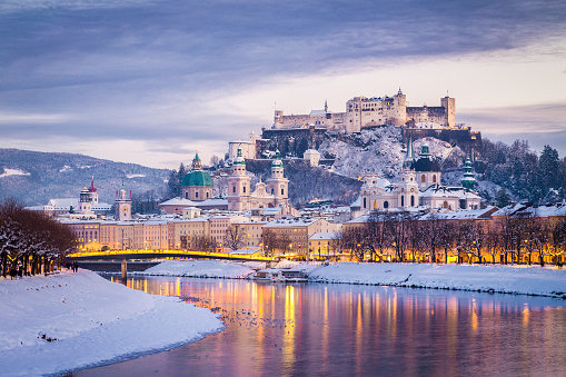 Classic view of the historic city of Salzburg with famous Festung Hohensalzburg and Salzach river illuminated in beautiful twilight during scenic Christmas time in winter, Salzburger Land, Austria