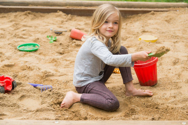 istock Little blond girl is playing in sandbox with plastic toy tools 646483524