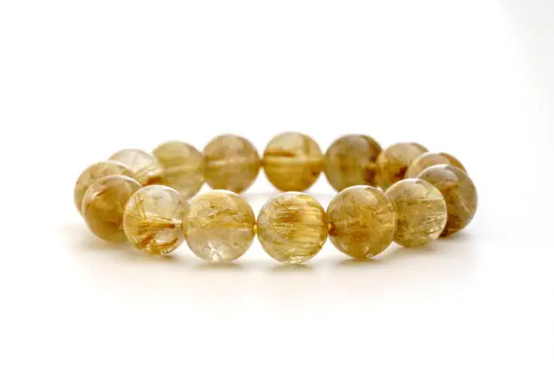 Beautiful translucent golden-yellow color Rutilated Quartz or Venus"u2019 hairstone bracelet on white background